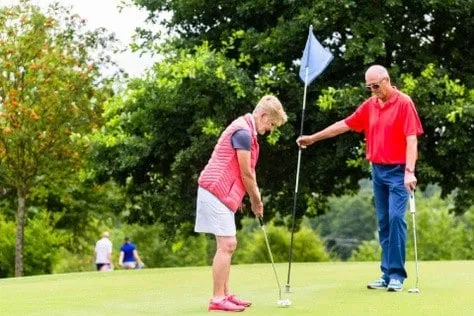 Elderly woman taking a swing at the golf park